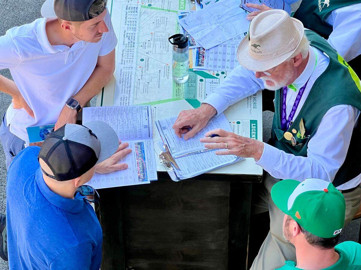 A Keeneland staff member helps fans place a horse racing bet during the 2024 Fall Meet opening weekend at Keeneland Race Course on Oct. 5, 2024, in Lexington, Ky. (Photo by James Crisp)