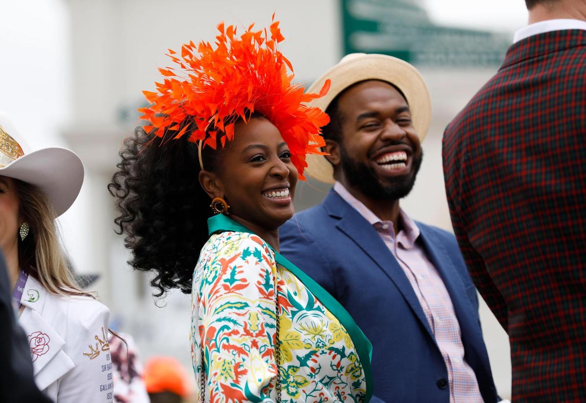 Britany and Gerald Prince, from Dallas, people watch at Churchill Downs in Louisville, Ky., Saturday, May 7, 2022. Britany’s orange fascinator came from The Hat Girls.