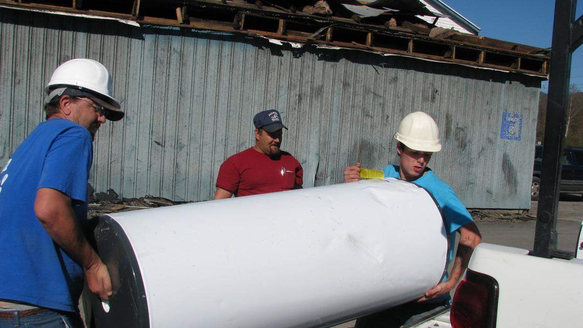 During  cleanup Thursday at Hickman Building Supplies Inc., Jimmy Givens, left, and Brandon Johnson, right, lifted a damaged water heater onto a pickup as fellow employee Glen Roesch watched. The three were moving  appliances from a shed that was destroyed in Tuesday's tornado in Middlesboro. Five of the business's 12 buildings sustained damage.      
