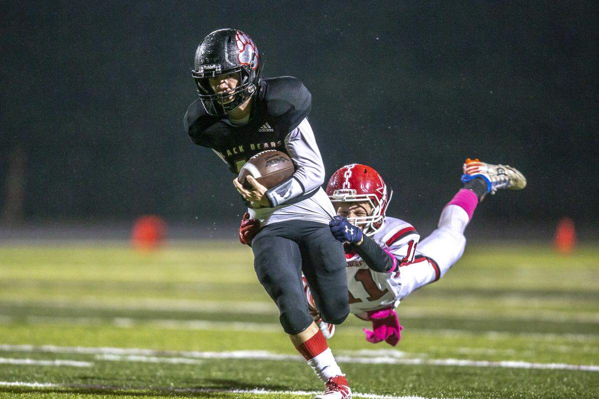 Harlan County’s Tyler Flanary runs the balls as Perry County’s Dawson Browning tries to bring him down.