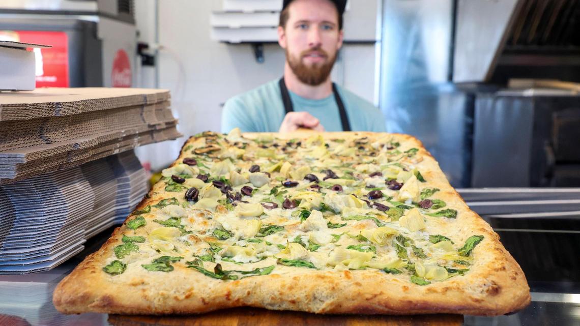 Andrew St. Clair holds a veggie pizza with white sauce, spinach, mushrooms, black olives, green peppers and mozzarella cheese at Dingbats Pizza, located at 471 Jefferson St., Thursday, Oct. 24, 2024 in Lexington, Ky.