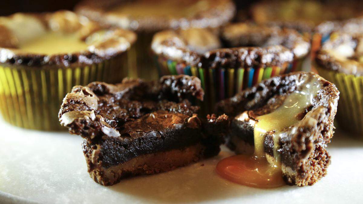 Reese’s Peanut Butter Cups nest in the bottom of these brownie cupcakes. Twix bars make a tasty substitute.