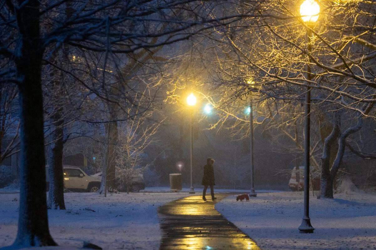 Pedestrians walk through Woodland park as snow falls in downtown Lexington, Ky., Wednesday, January 27, 2021. The National Weather Service has predicted a low of 20 degrees Wednesday night and a high of 32 Thursday.