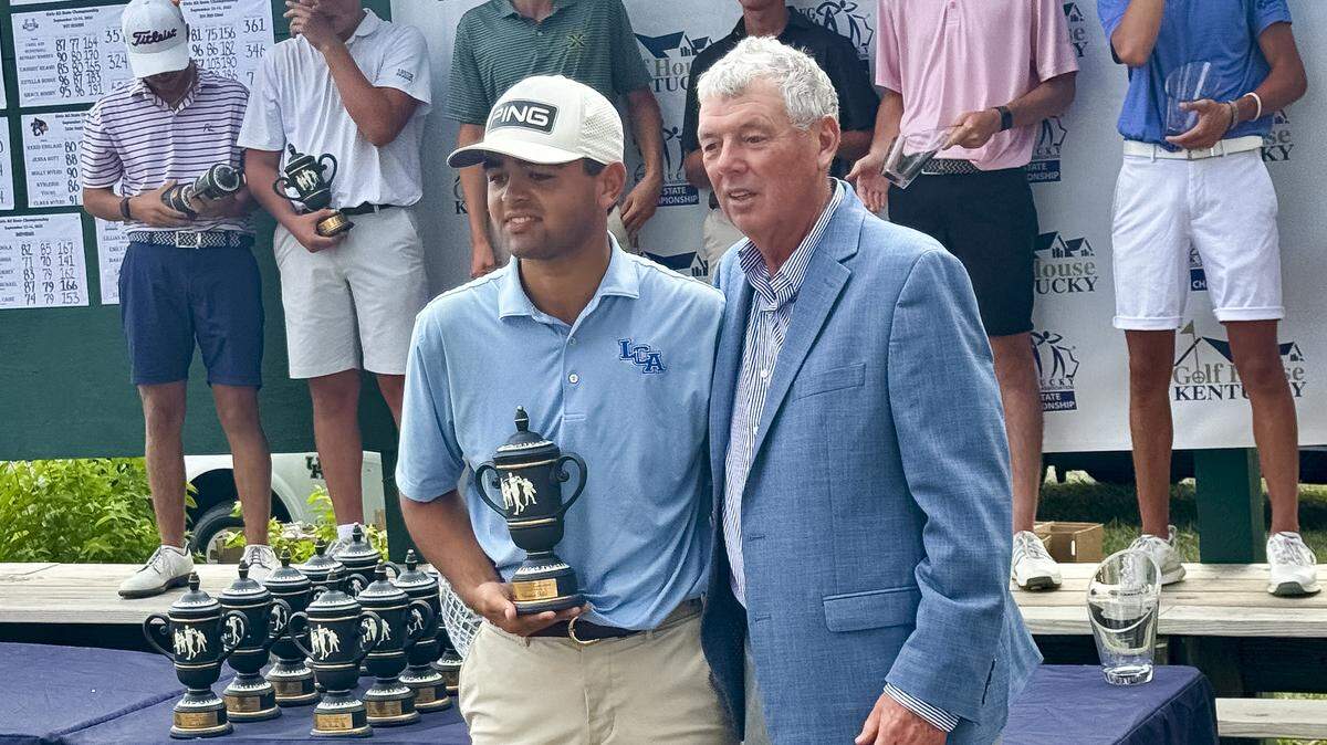 Lexington Christian’s Parker Geldhof, left, accepts the first-place trophy from Wes Martin, co-executive director of the Kentucky Golf Coaches Association, after winning the boys individual title of the All State Championships at the University Club of Kentucky on Sunday.