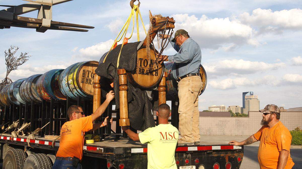 Giddyup, part of The Bourbon Barrel Project on Town Branch, was placed on a truck Sunday evening, then taken to its spot in Triangle Park. Roy Rivera, on truck, of Wilhite Ltd. and others helped secure each piece for transport.