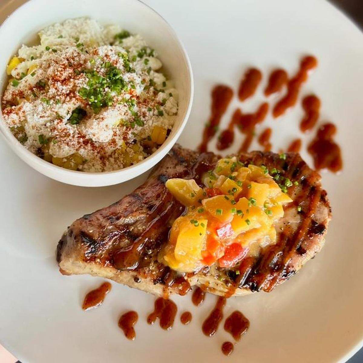 Pork Chop with grilled corn “elotes”, peach mostarda and barbecue gastrique from Bella Cafe & Grille