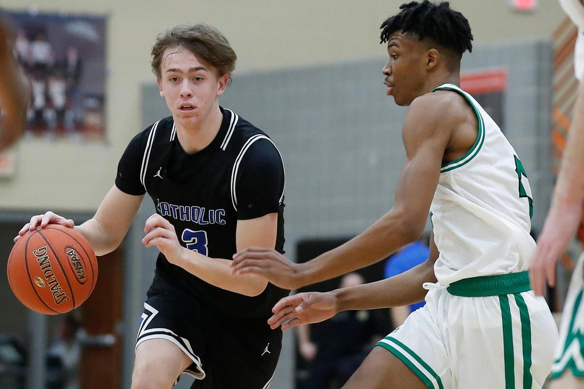 Lexington Catholic’s Jack Gohmann (3) dribbled past Paul Laurence Dunbar’s Tim Hall (23) during Thursday’s game at Dunbar. The Knights won 69-67.