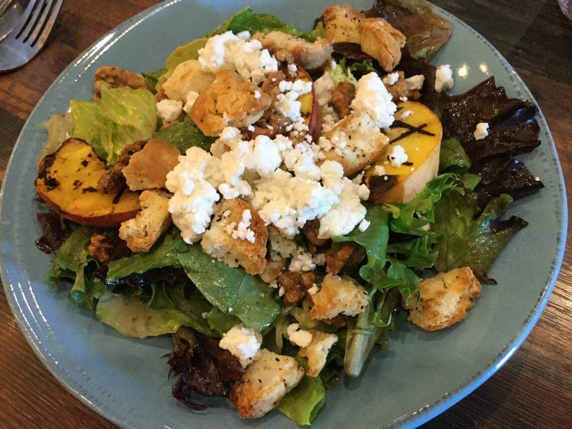 The menu includes salads such as Nash’s Summer Salad, with grilled peaches, Capriole Farms goat cheese, peppered biscuit croutons and sweet bourbon vinaigrette.
