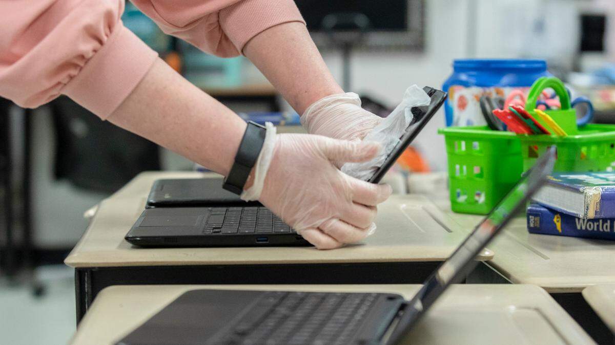 A teacher used a disinfectant wipe to clean a computer at Harrison County Middle School in Cynthiana.