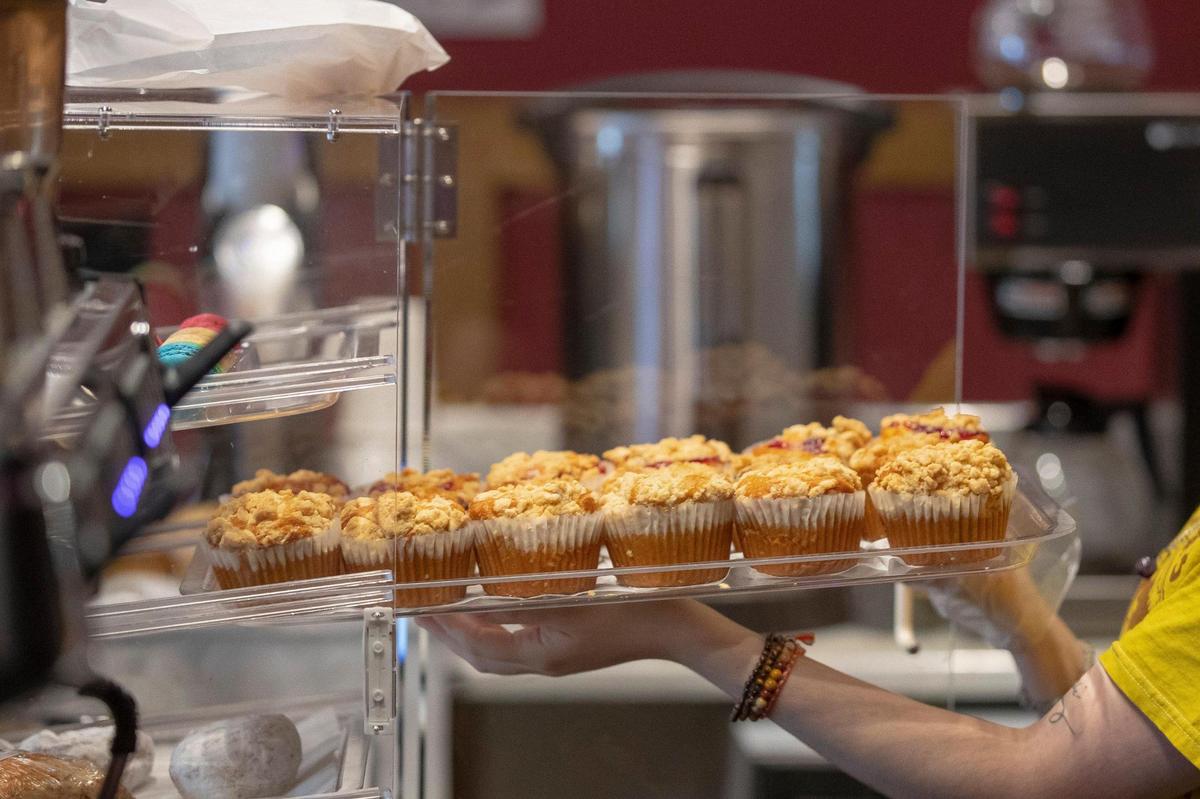 Bee Rivera, a barista at The Creatures’ Cauldron Cafe at 128 N Broadway in Lexington, Ky., puts muffins in a display case at the cafe on Thursday, Sept. 22, 2022.