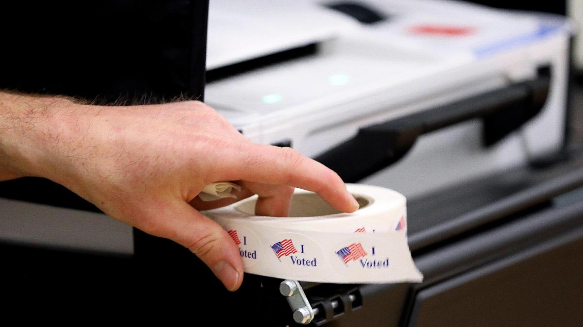 A precinct worker holds a roll of “I Voted” stickers next to a voting machine as voters cast their ballots at Clays Mill Elementary School on May 16, 2023, as Kentucky went the polls on primary election day across the state.