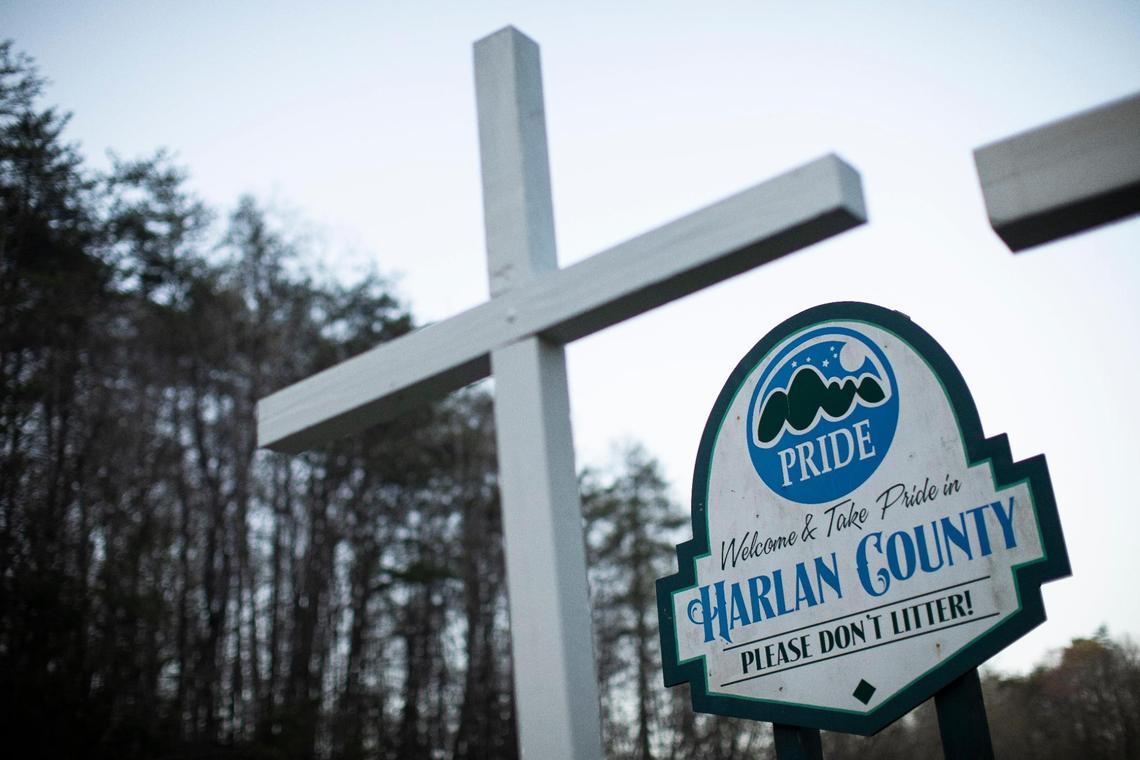 The sign welcoming drivers to Harlan County from Bell County is framed by wooden crosses painted white in Harlan, Ky., Friday, April 9, 2021.