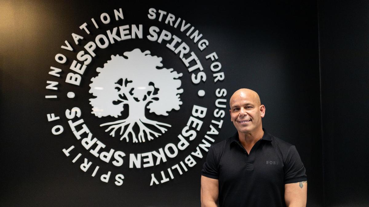 Bespoken Spirits CEO Peter Iglesias poses in front of a wall sign within the distillery’s tasting room In Greyline Station on West Loudon Avenue, March 20, 2024.