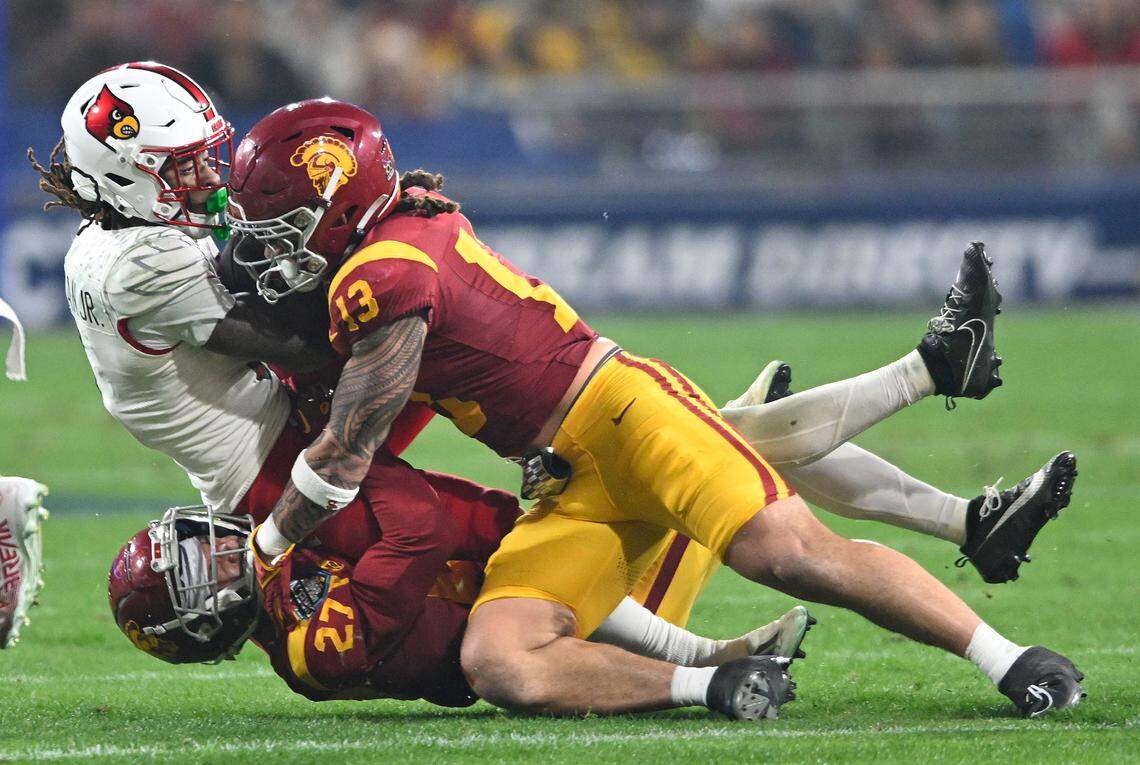 Louisville wide receiver Kevin Coleman (3) is tackled by Southern California safety Bryson Shaw (27) and linebacker Mason Cobb (13) during the Holiday Bowl in San Diego on Dec. 27.