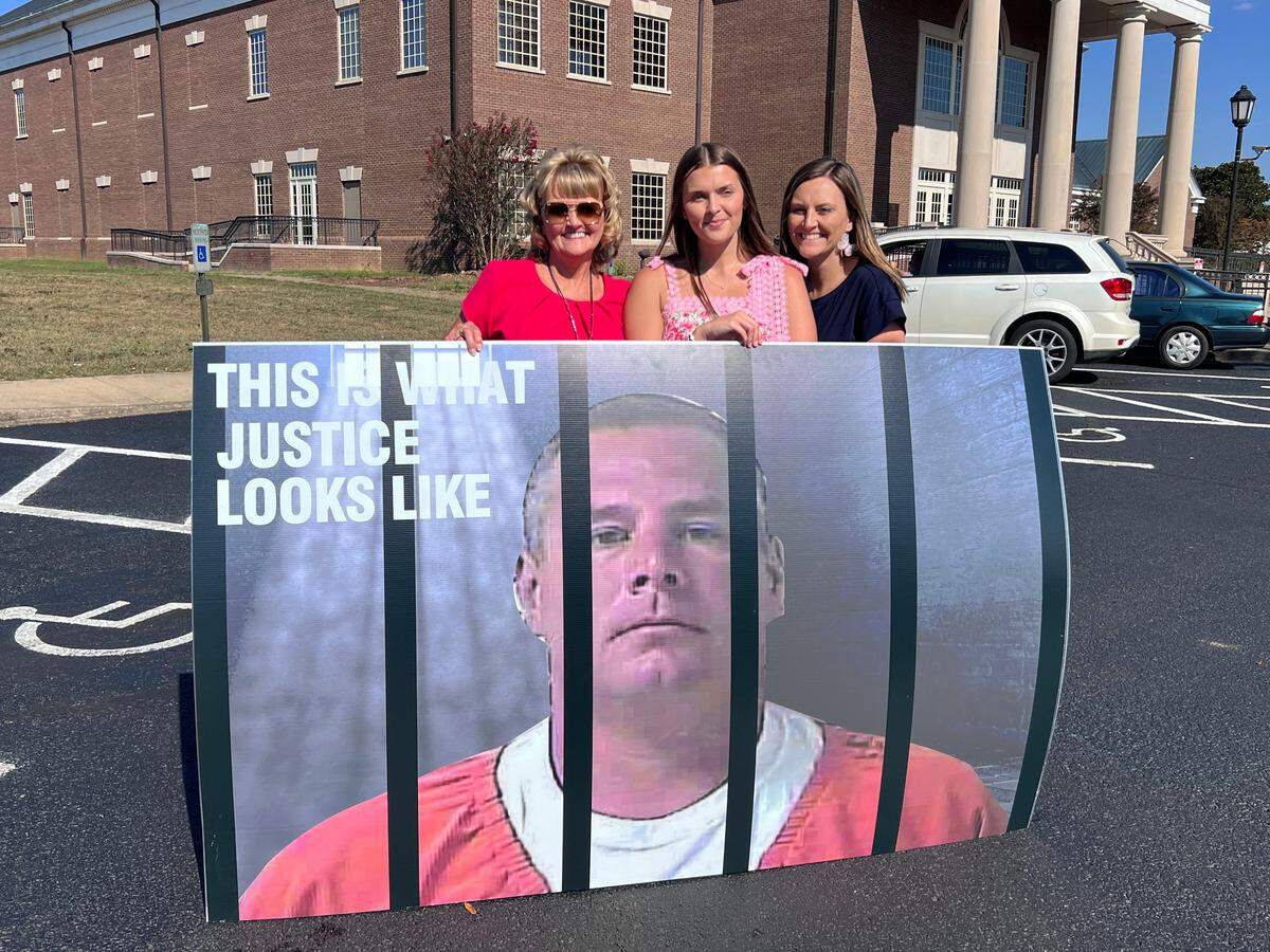 Mother of Crystal Rogers, Sherry Ballard, stands with family members holding a sign featuring Brooks Houck behind bars outside the Bardstown Courthouse on Sept. 17, 2025, in Bardstown, Ky.