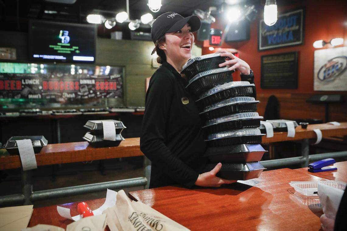 Meredith Johns, of Lexington, Ky., laughs with a coworker while preparing a takeout order at Malone’s Steakhouse in Lexington, Ky., Saturday, March 21, 2020. All orders at Malone’s and Drake’s will be delivered to customers curbside.