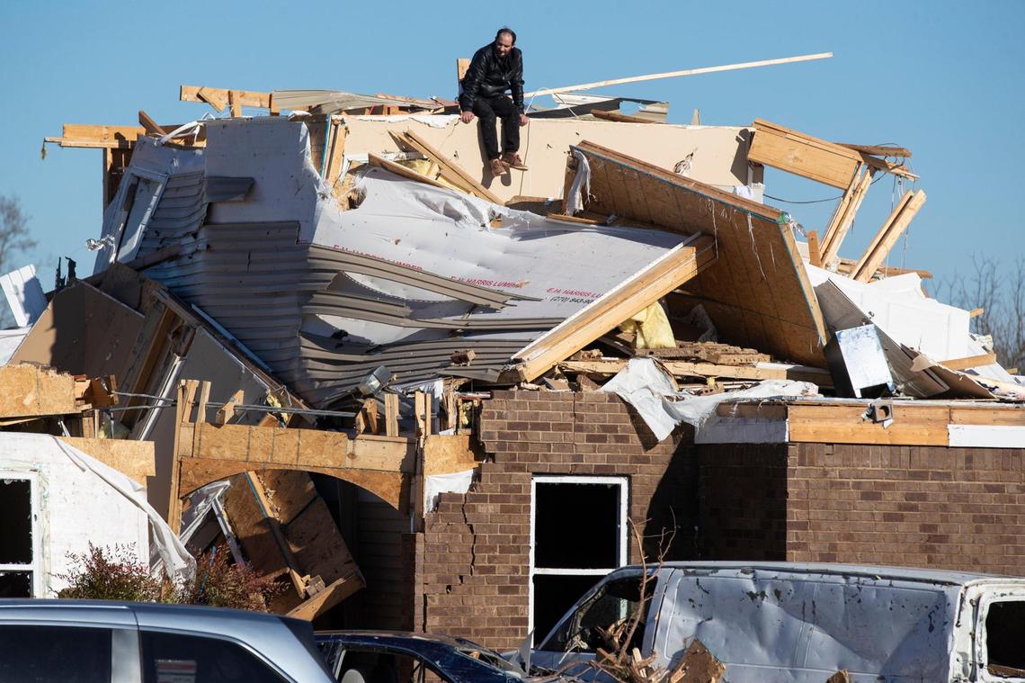 A man sits on top of a destroyed apartment building after a tornado swept through Friday night in Bowling Green, Ky., Sunday, December 12, 2021.