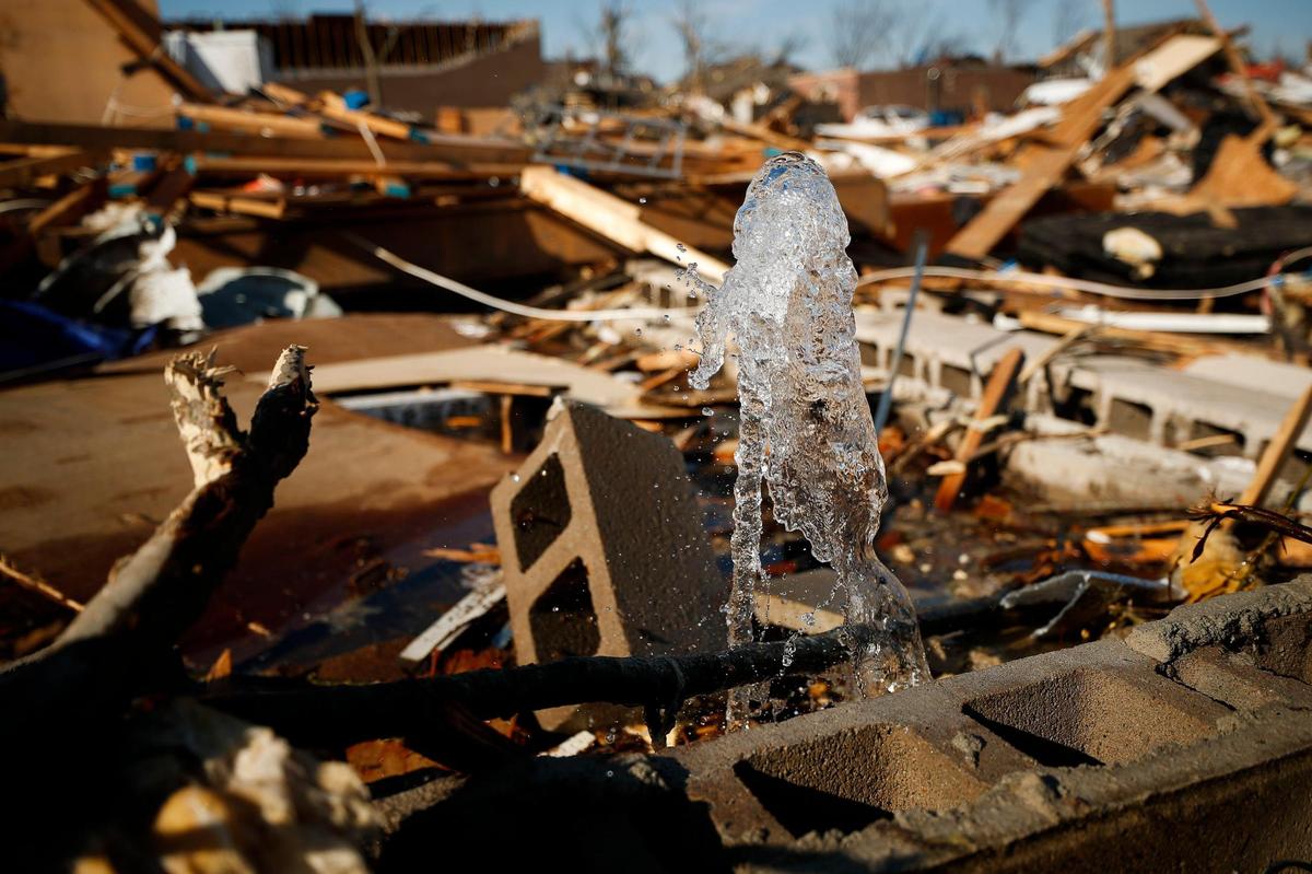 A broken waterline spews water from the rubble of a home on North 6th Street in Mayfield, Ky., Tuesday, Dec. 14, 2021.