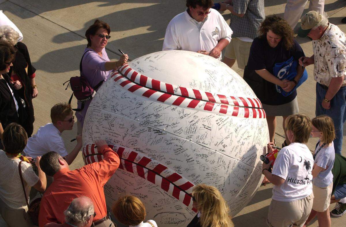 Fans sign a giant baseball outside Applebee’s Park at the Lexington Legends’ home opener on April 9, 2001.