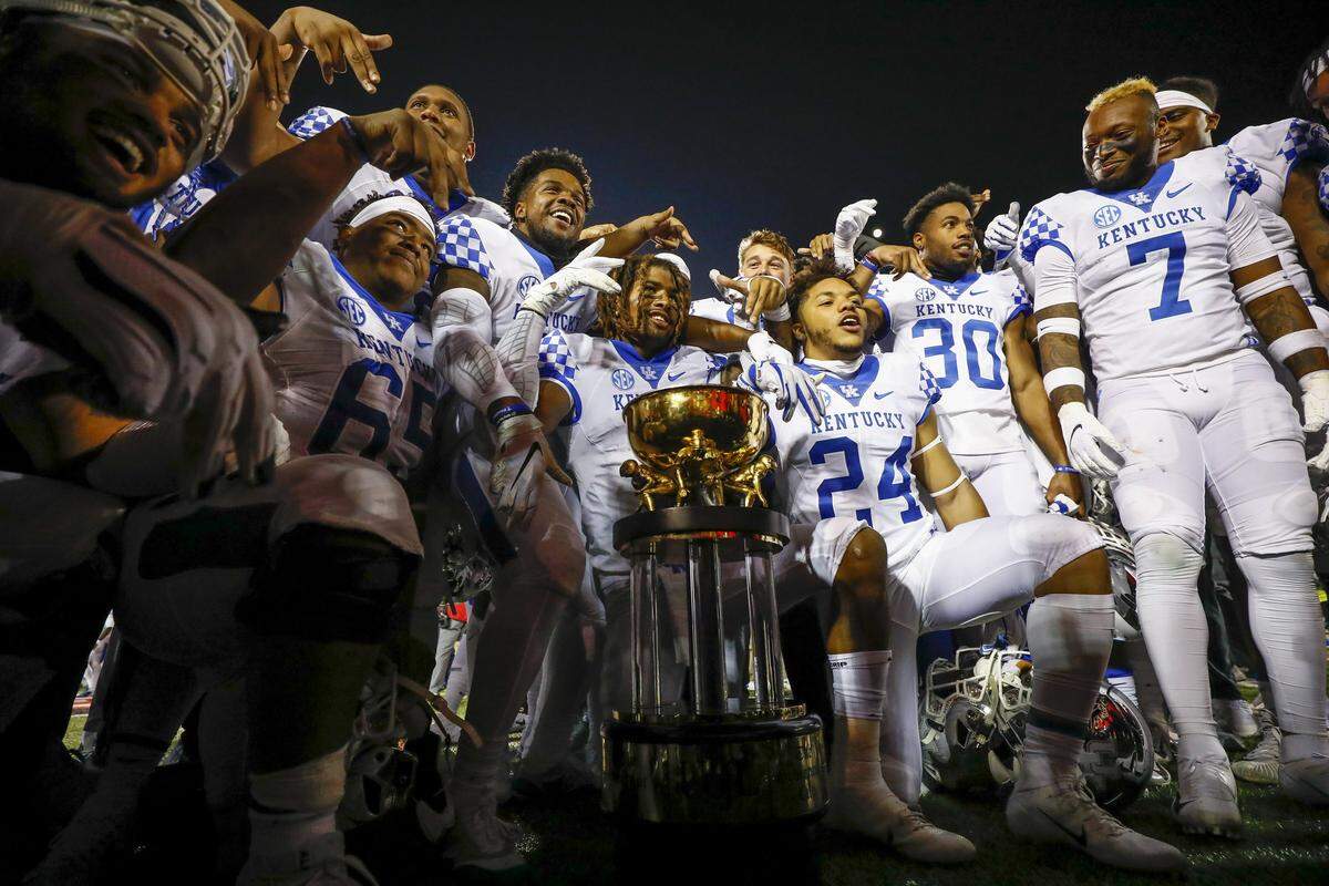 Kentucky football players celebrated around the Governor’s Cup trophy after the Wildcats blasted Louisville 56-10 last season.