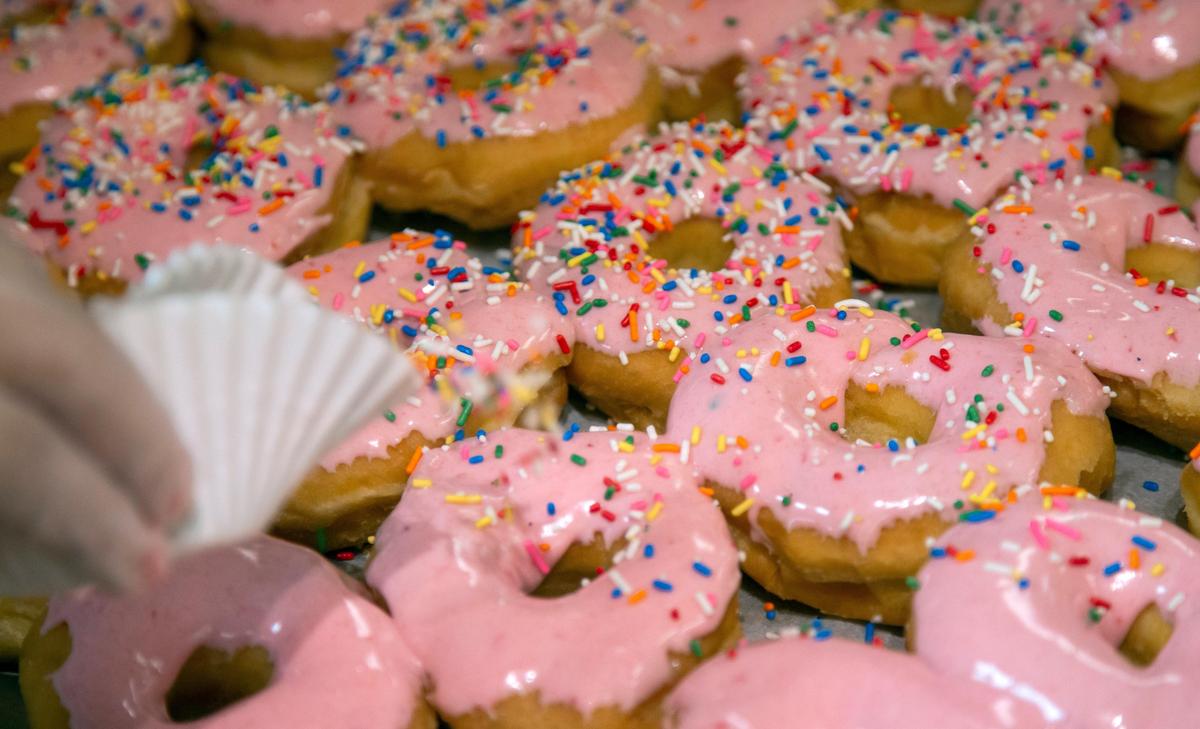 Robin Murphy decorates strawberry sprinkle yeast donuts at Donut Days Bakery in advance of National Donut Day on June 5.