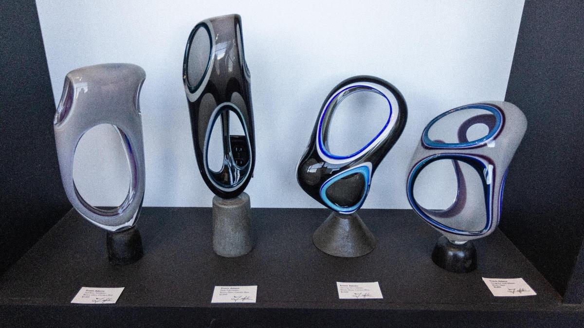 Four blown glass artworks by artist Travis Adams featured in the gallery space within the Trifecta Glass Art Lounge. Pieces inside are on display for sale.