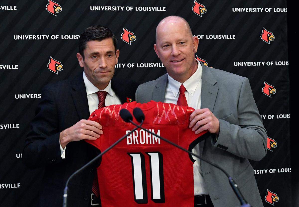 Louisville athletic director Josh Heird, left, presented then-newly named football coach Jeff Brohm with a U of L jersey on Dec. 8, 2022. With the firing of Kenny Payne, Heird and U of L are now in the market for a new head men’s basketball coach.