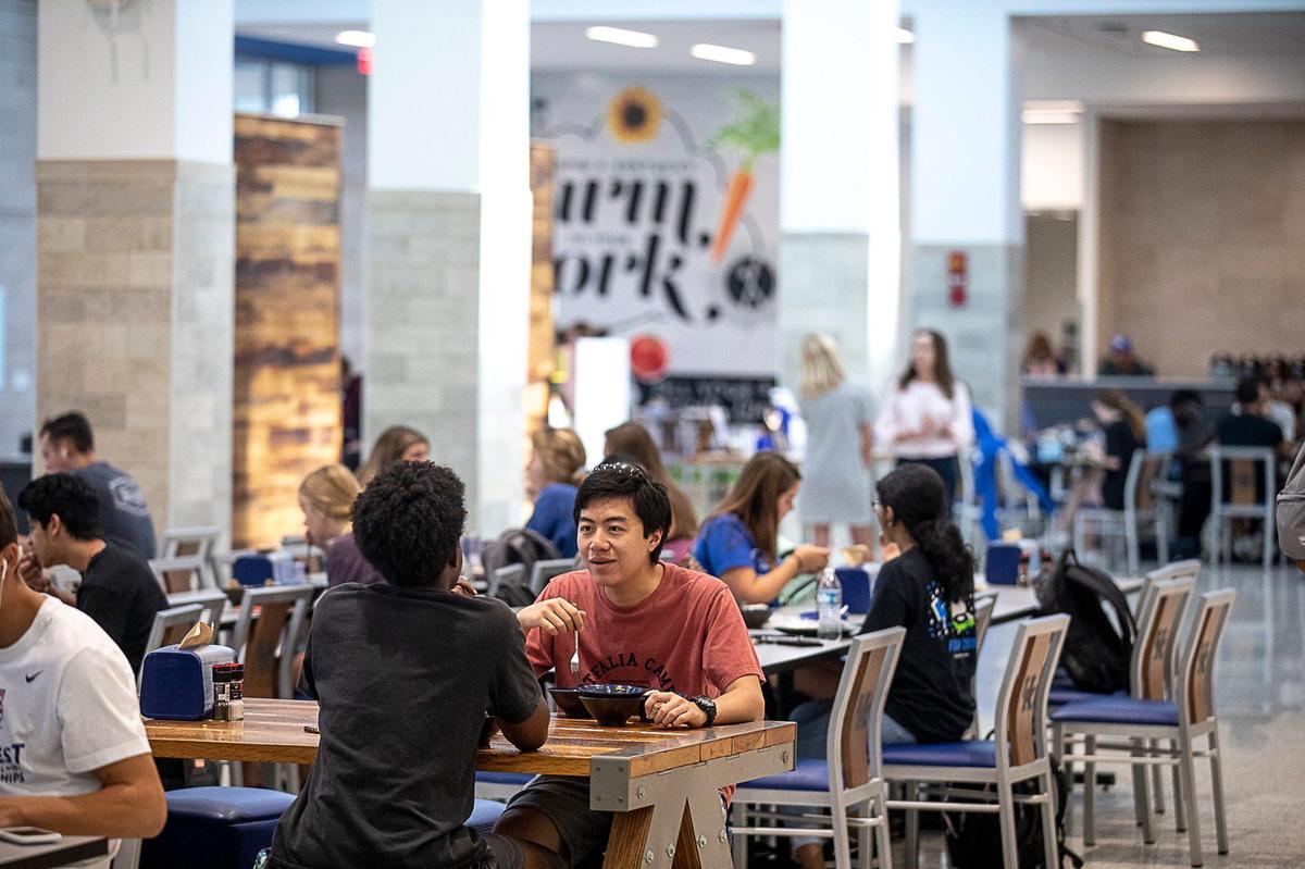 Matthew Wirasakti, with fork, talks with Luke Taylor, both first-year students at the University of Kentucky, while eating lunch Wednesday at The 90 on UK’s campus.