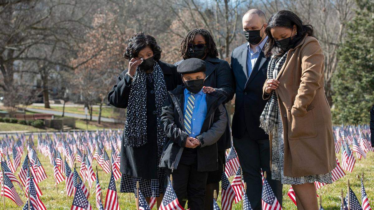 Tanya Smith, left, honored her late husband, the Rev. Gregory Smith, of Louisville, by placing a flag at the Capitol during a memorial marking the one-year anniversary of the first recorded case of COVID-19 in Kentucky Saturday.