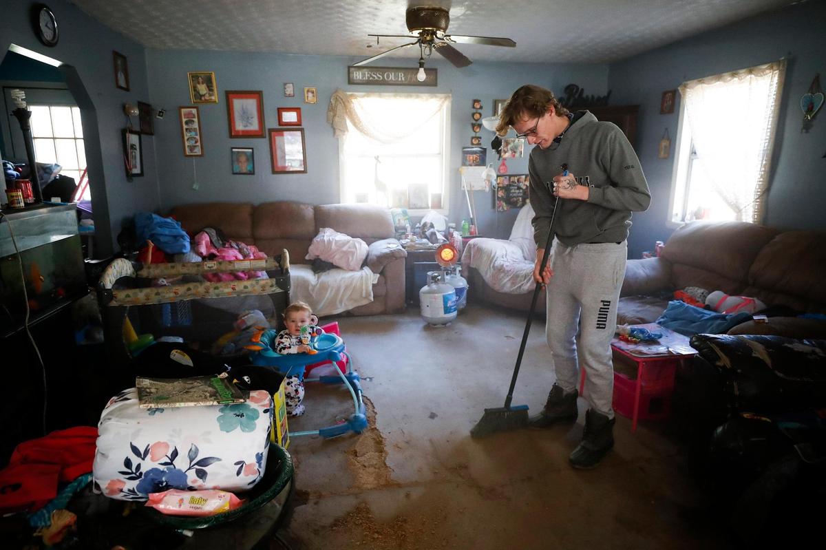 Joey Smith sweeps dirt from the living room in his trailer following the Big Creek flood in Sidney, Ky., Thursday, Jan. 13, 2022. Smith was home with other family members as the trailer flooded.