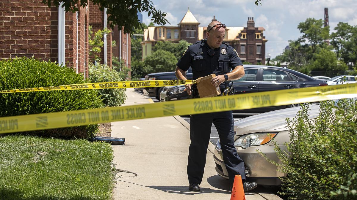 Lexington police officer Nicholas Gray puts up crime scene tape where a shooting was reported near the Newtown Crossing apartment complex in Lexington, Ky., on Wednesday, June 26, 2019.