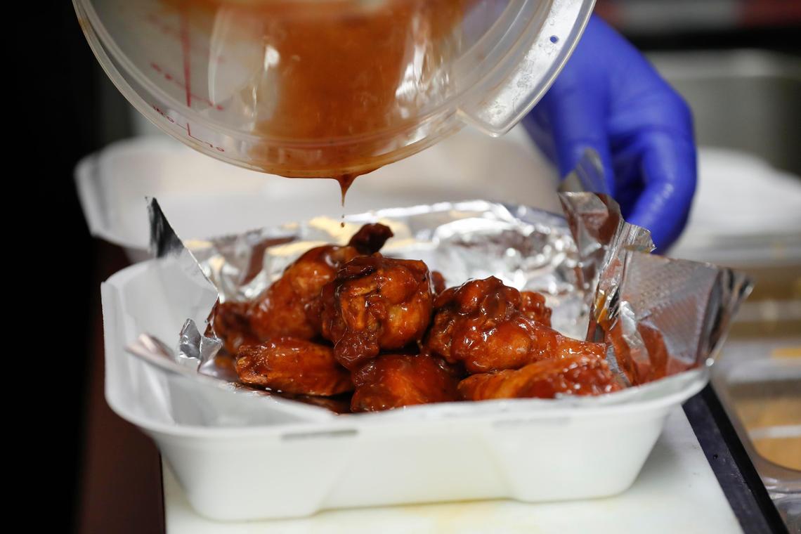 Kitchen manager Steve Tiynan pours sweet barbecue sauce on an order of smoked wings Friday, May 15 at J. Render’s Southern Table & Bar.