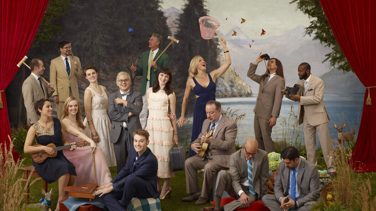 Pink Martini founder Thomas Lauderdale, wearing a bow tie, stands in the midst of The von Trapps (yes, those von Trapps). The five of them are surrounded by members of Pink Martini.