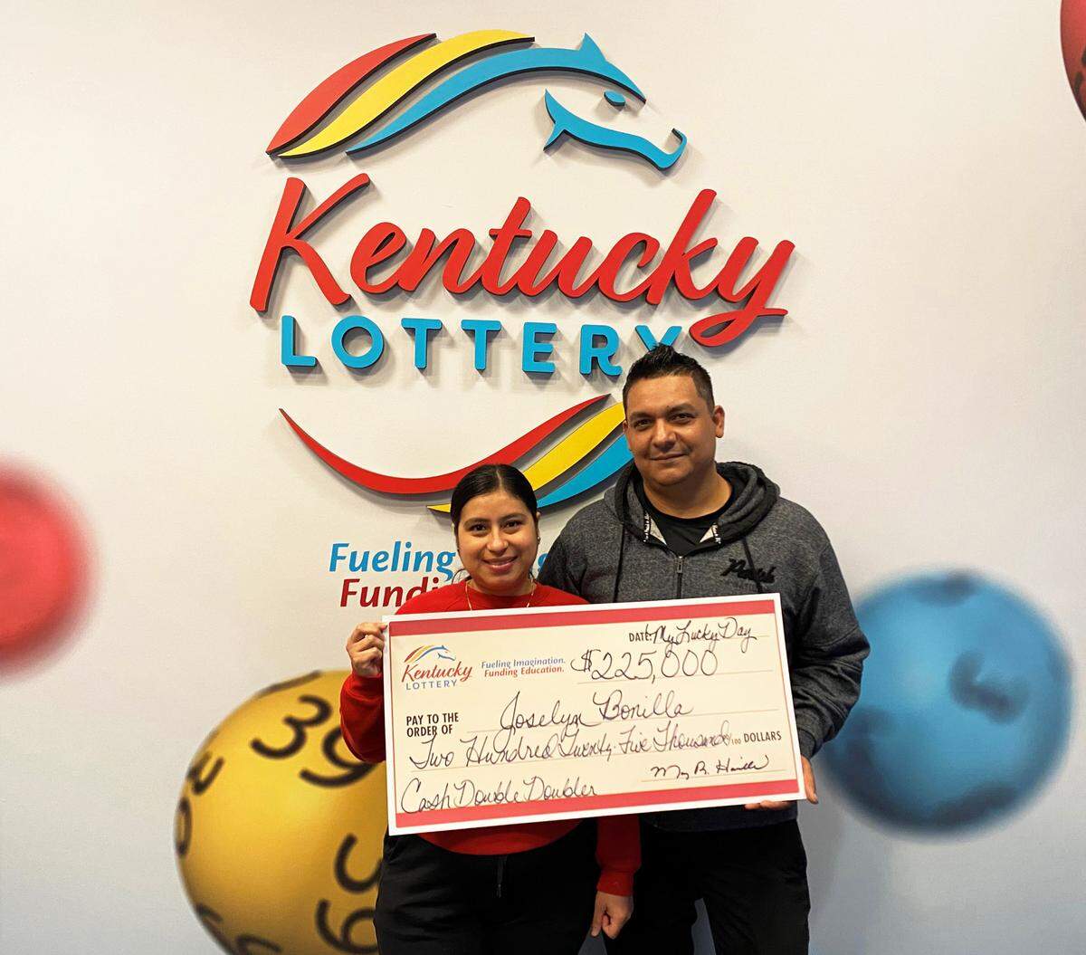 Joselyn Bonilla and her husband, of Louisville, pose with their big check after a $225,000 win on a Kentucky Lottery scratch-off ticket Monday.
