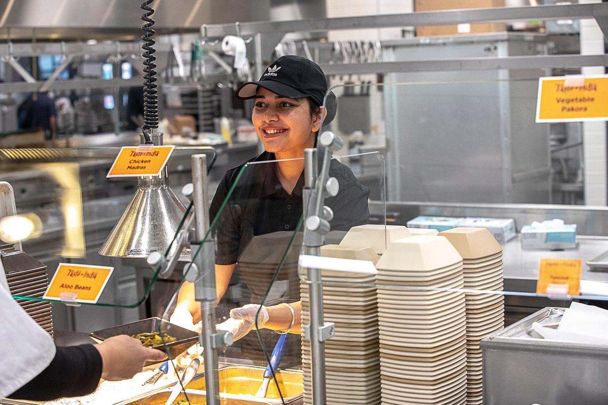 Pawandeep Kaur Gill serves a bowl of aloo beans Wednesday at Taste of India’s location at The 90 on the University of Kentucky campus.