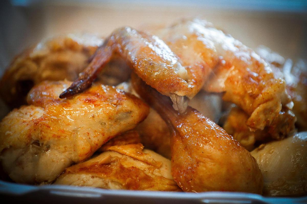 A chicken combo features a prepared rotisserie chicken, two sides, tortillas and salsa at Rosticeria Doña Coco.