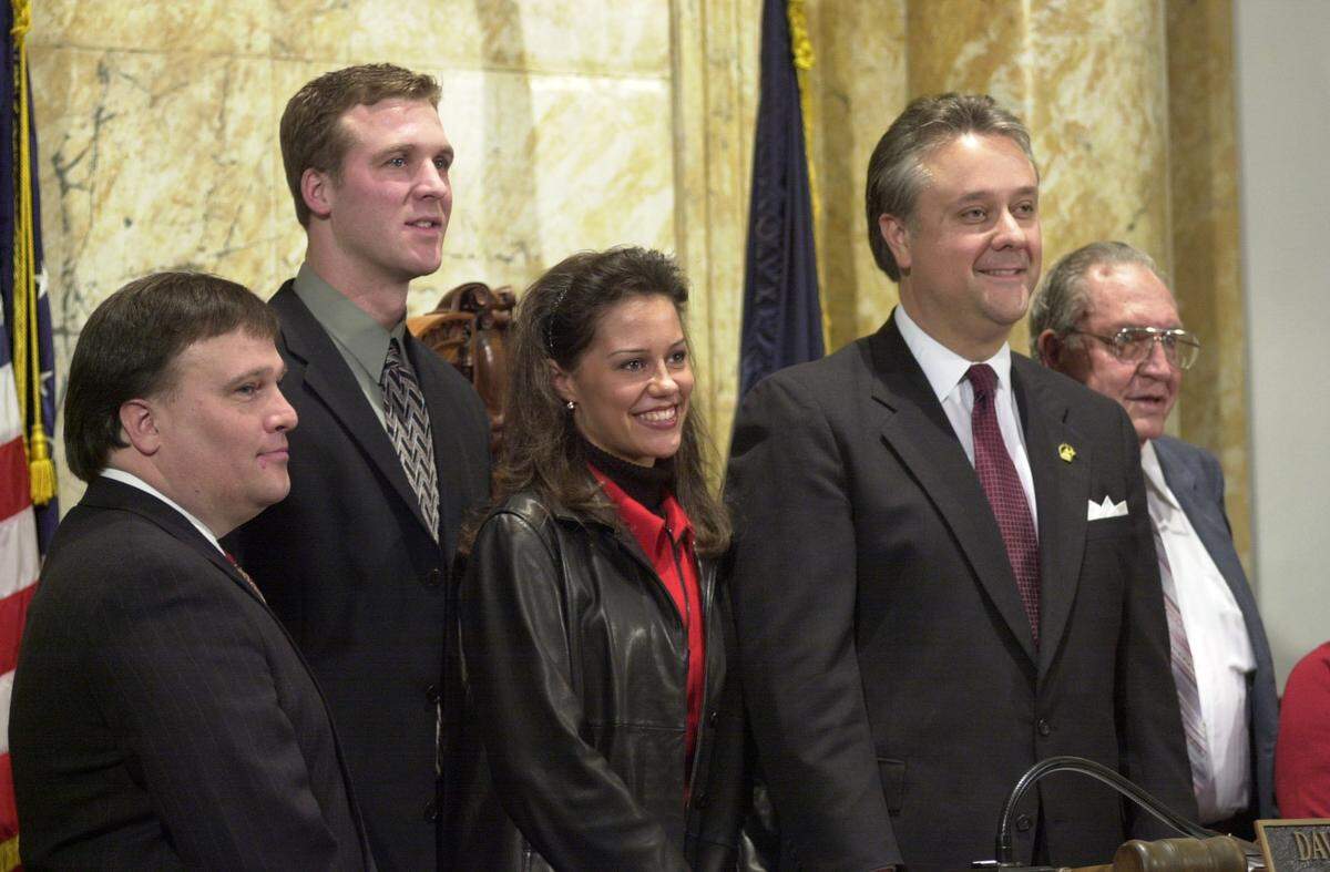 Jan. 18, 2000. Senate chamber, Capitol building, Frankfort: Senator Robert Stivers, R-Manchester, introduced a resolution naming the "Hyden Spur", Ky. 118, as "Tim Couch Pass.” Stivers (left) is pictured with the Couch family and then-Senate president David Williams (center right).