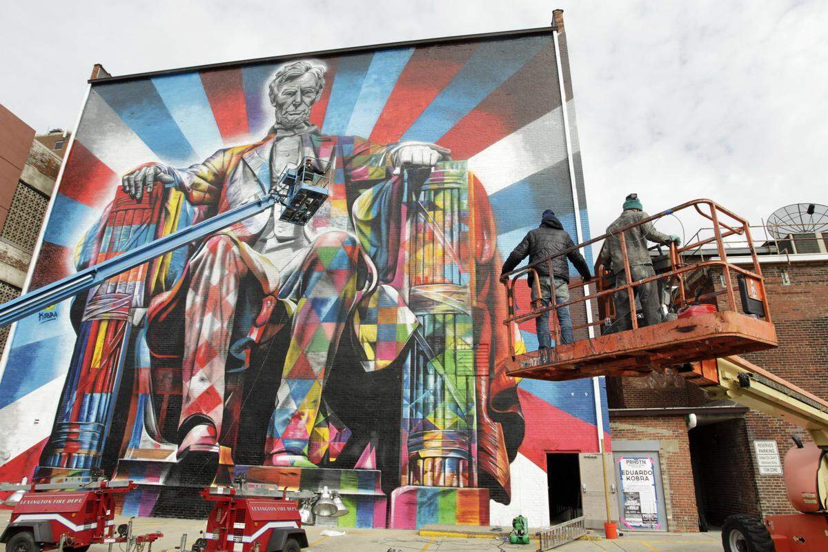 Artists Cesar Goncalves de Almeida, at left, Eduardo Kobra, center, and Agnaldo Brito Periera, right, moved their platforms into place to finish the Lincoln mural on the back of the Kentucky Theatre in 2013.