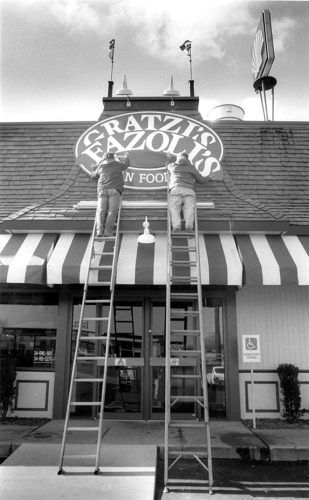Martin Sherrod, left and Clint Sherrod of the Sherrod Sign Company change the sign on Gratzi’s, on North Broadway in Lexington, to it’s new name, Fazoli’s, February 10, 1989. The companies first Italian fast-food first restaurant on North Broadway near the Interstate 75-64 interchange, had been operated by Jerrico under the Gratzi’s name since September 1988. But surveys of potential customers showed that they kept confusing “Gratzi’s” - taken from the Italian word for “thank you” - with the name of Canadian-born hockey player Wayne Gretzky, said Robert L. Sirkis, Jerrico’s executive vice president. After hiring three naming firms and looking at tens of thousands of names, Jerrico decided to replace Gratzi’s with Fazoli’s. Which means . . . nothing. “It is completely made up,” Sirkis said. Photo by Clay Owen | staff