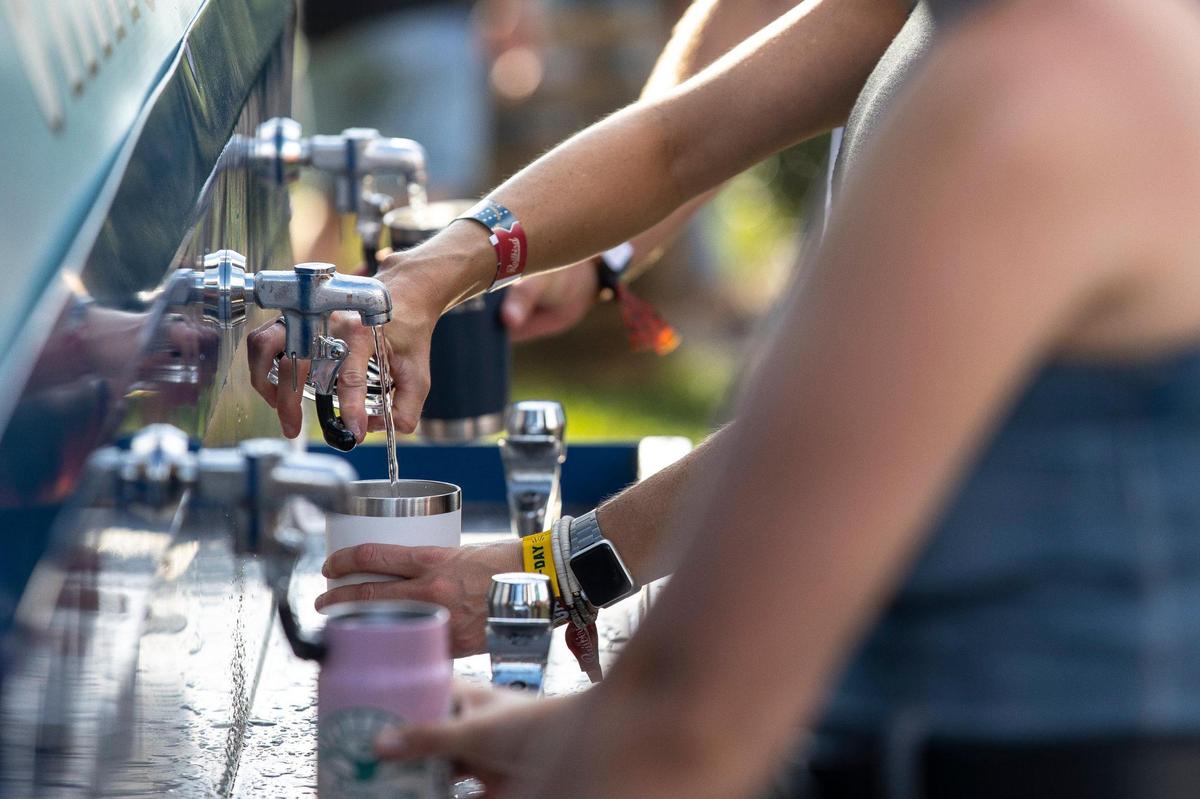 People wait in line to get water at a water refill station at the Railbird Festival at Keeneland in Lexington, Ky., on Saturday, Aug. 28, 2021.