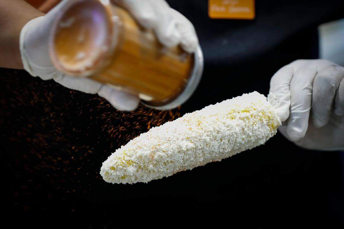 Michael De la Cruz, of Lexington, Ky., prepares Elotes with an ear of corn on a stick slathered in mayonnaise and topped with lime juice, cotija cheese and chili powder at Taqueria De La Cruz at the Lexington Lions Club’s Bluegrass Fair at Masterson Station Park in Lexington, Ky., Friday, June 11, 2021.