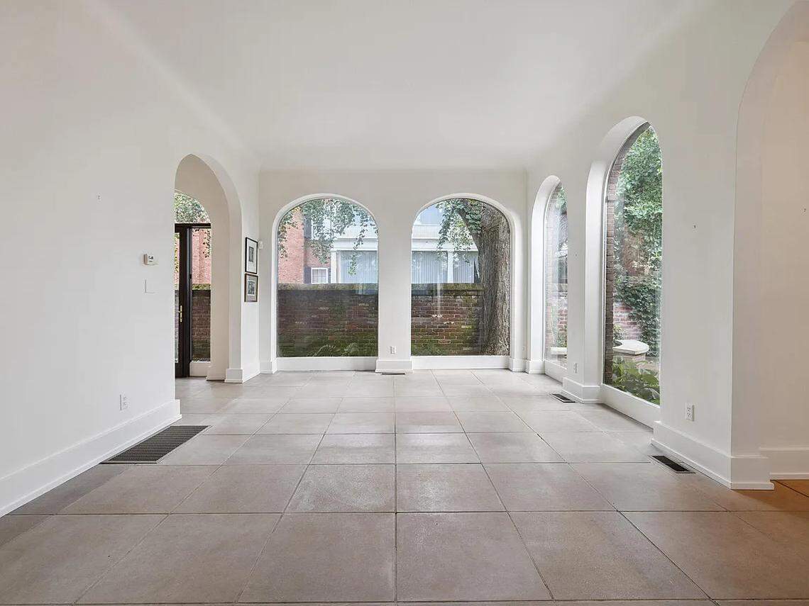 A view of the sun room at 220 Market Street, which looks out onto the home’s private courtyard. There are large, arching windows that extend down to the floor, offering grand views of the courtyard outside.