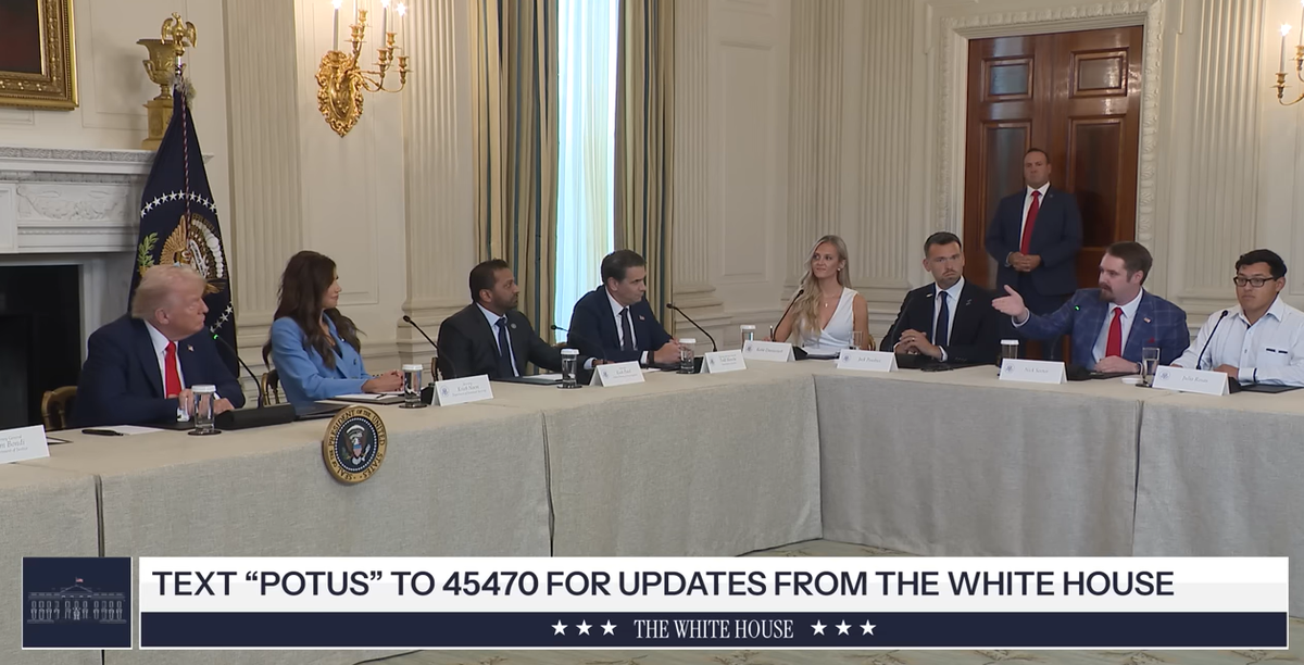 Nick Sortor, right, in blue suit, speaks to President Donald Trump at a White House roundtable discussion in October