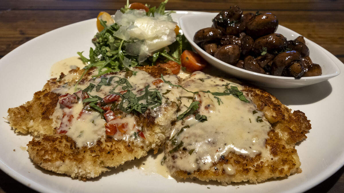 Parmesan crusted chicken ($26.85), topped with sun-dried tomato sauce and a side of port mushrooms at Firebirds Wood Fired Grill.