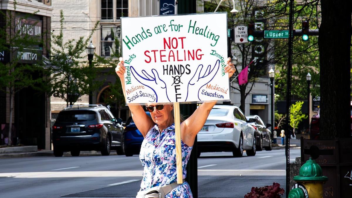 A protester holds a sign advocating “healing hands” being used for effective social services during the “No Kings Then, No Kings Now” Peaceful March and Protest in front of the Robert F. Stephens Courthouse, downtown Lexington, Ky, on April 19, 2025.
