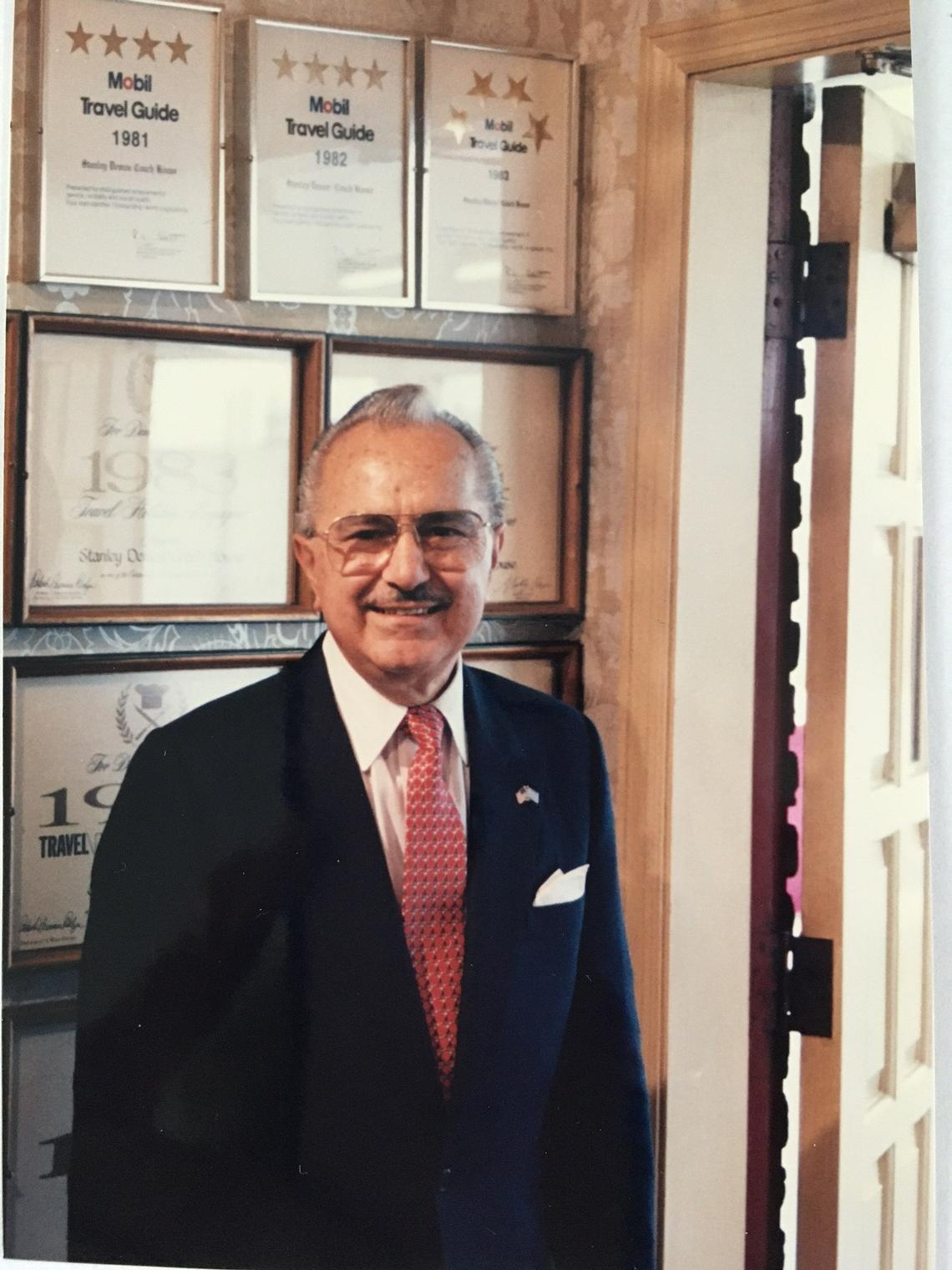 Stanley Demos in the entry of the Coach House on South Broadway in front of the many awards and honors that the restaurant earned over the decades.