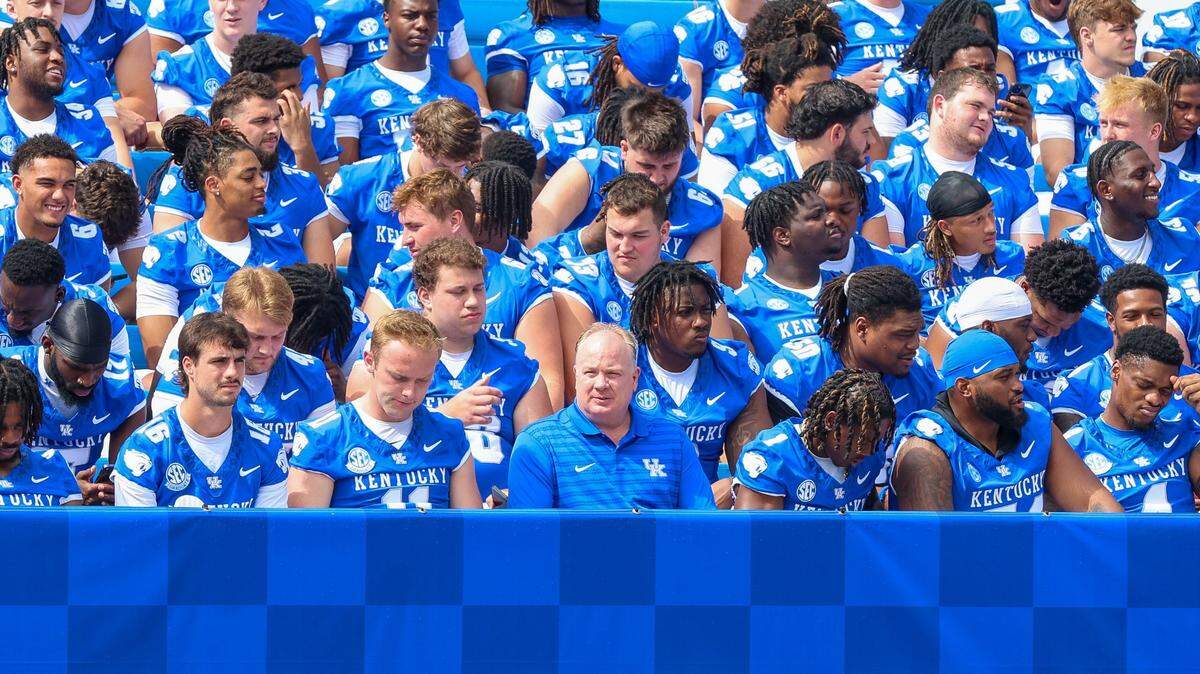 University of Kentucky head football coach Mark Stoops, center of bottom row, and his players prepare for a team photo Friday at Kroger Field.