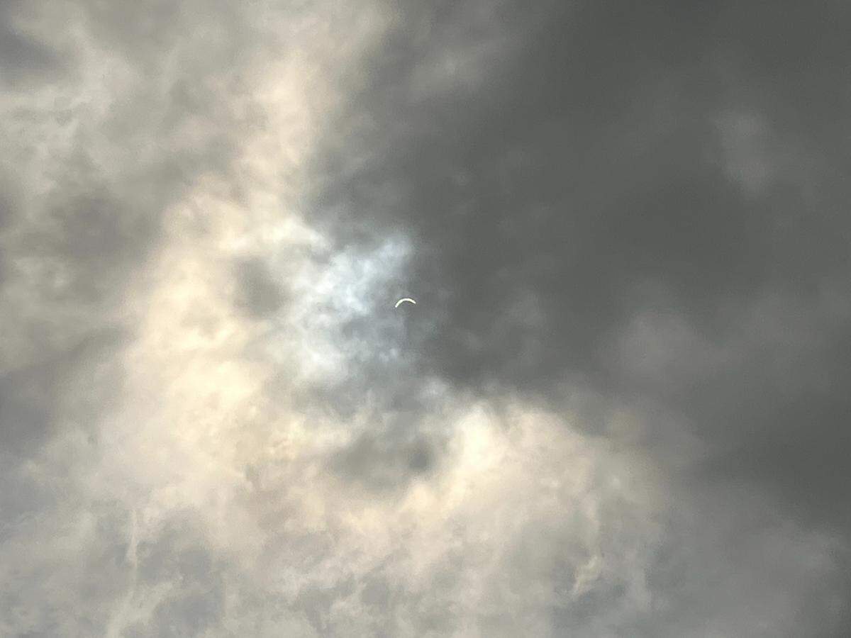 A partially eclipsed sun peaks through a cloudy sky over Lexington, Ky. on April 8, 2024
