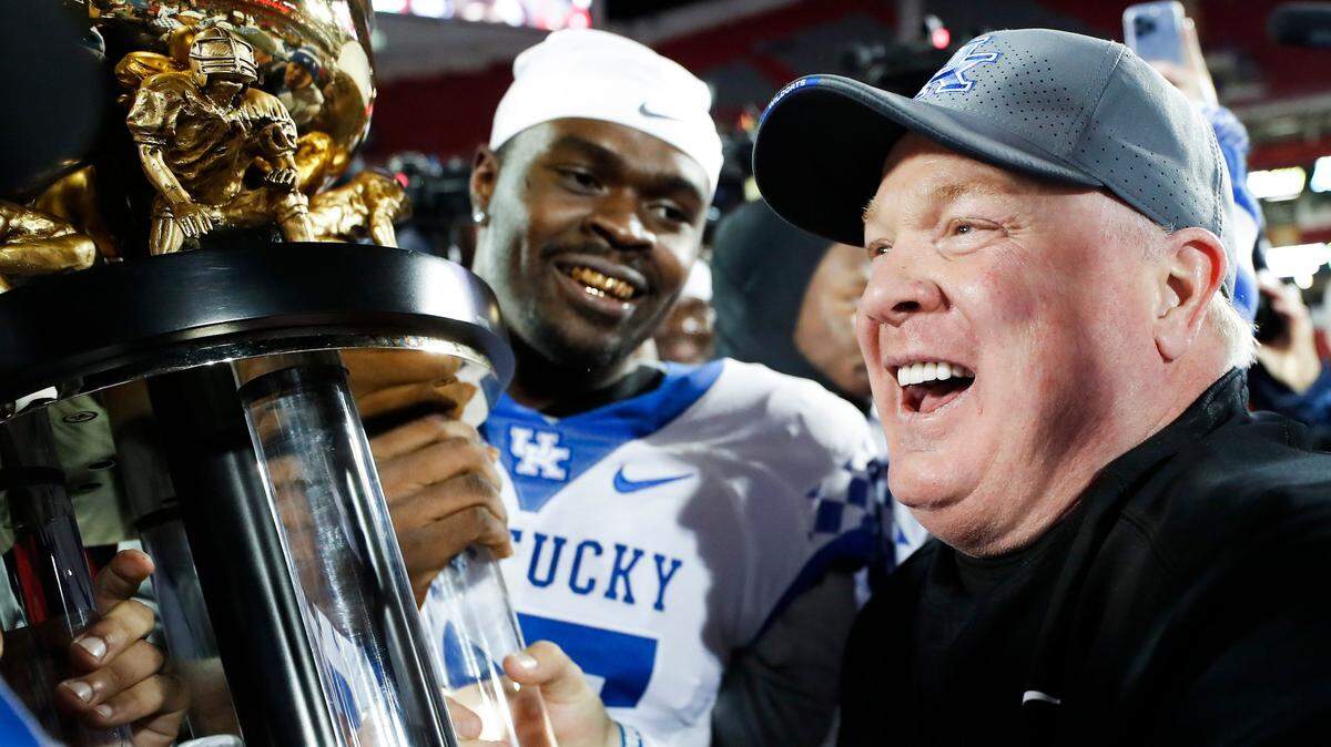Kentucky Coach Mark Stoops celebrated with the Governor’s Cup trophy after defeating intrastate rival Louisville 52-21 at Cardinal Stadium in the 2021 regular-season finale. UK has beaten U of L in four of the past five meetings.