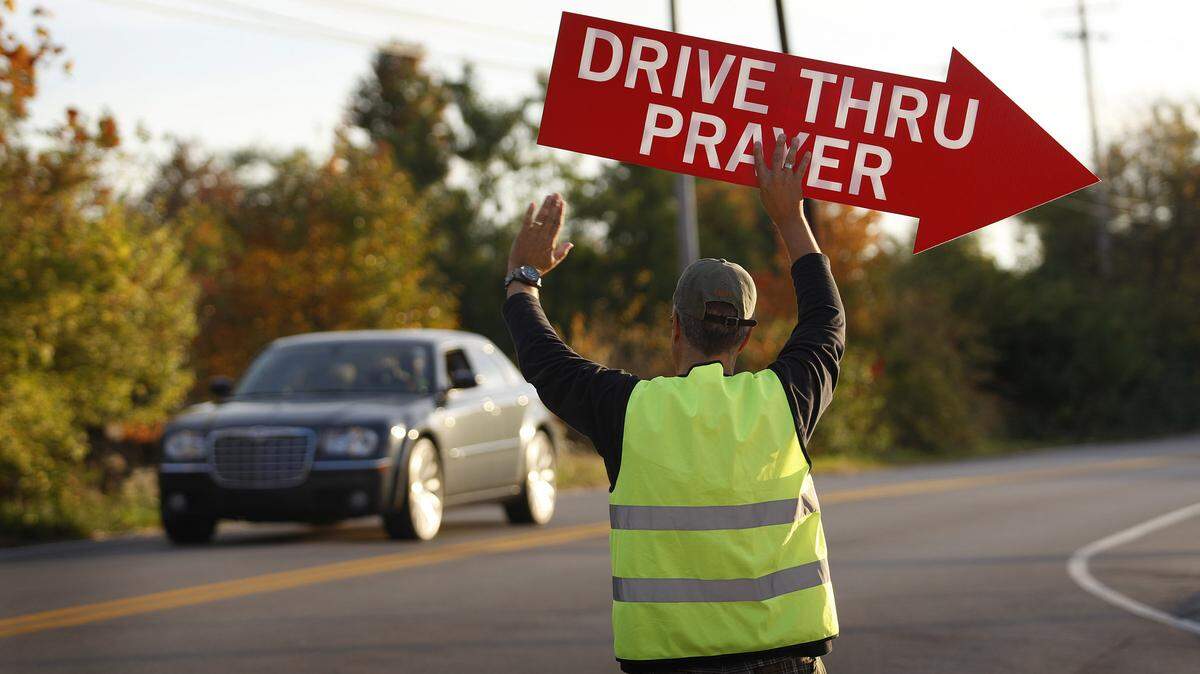 Rex Hughes used a sign on Greendale Road to encourage passing motorists to stop in during a drive-through prayer service. Centerpointe Christian Church offers the service once a month, but it might be expanded to a weekly basis.